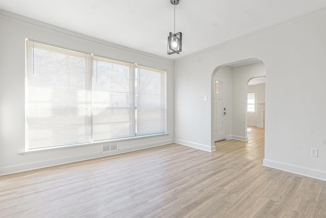 spare room with plenty of natural light, ornamental molding, and light hardwood / wood-style floors