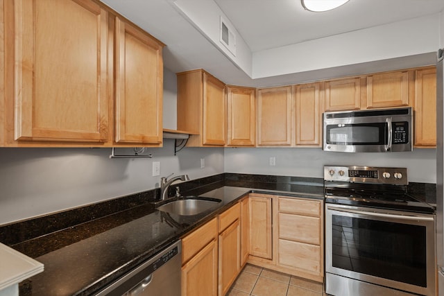 kitchen featuring sink, light tile patterned floors, stainless steel appliances, dark stone counters, and light brown cabinets