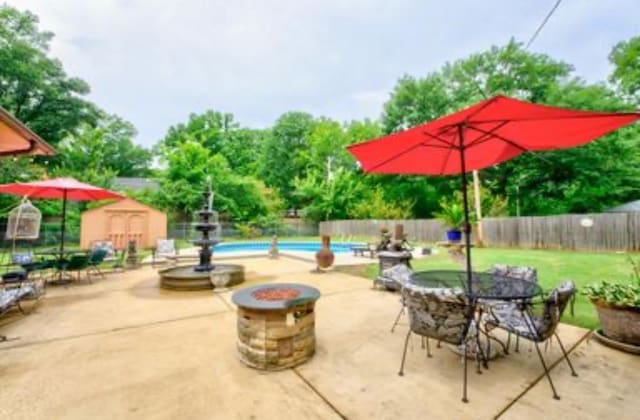 view of patio with a storage shed, a fenced in pool, and a fire pit