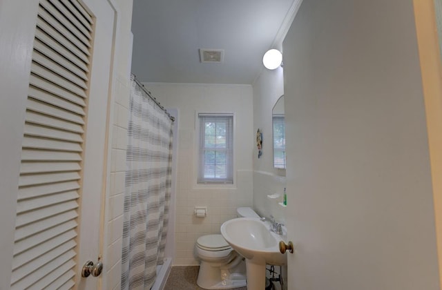 bathroom featuring toilet, sink, tile walls, ornamental molding, and curtained shower