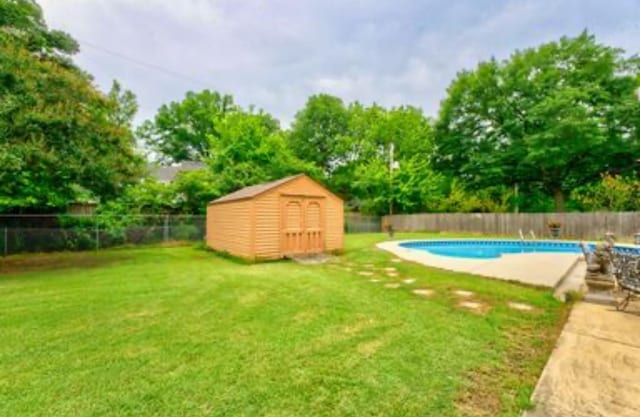 view of yard with a fenced in pool and a storage unit