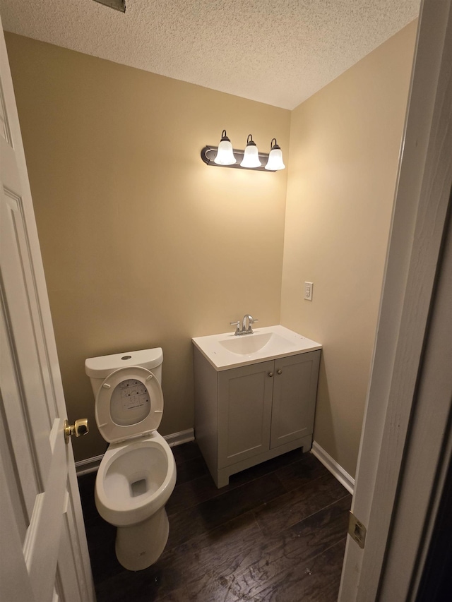 bathroom featuring vanity, hardwood / wood-style floors, toilet, and a textured ceiling