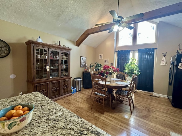 dining area featuring high vaulted ceiling, a textured ceiling, ceiling fan, beam ceiling, and light hardwood / wood-style floors