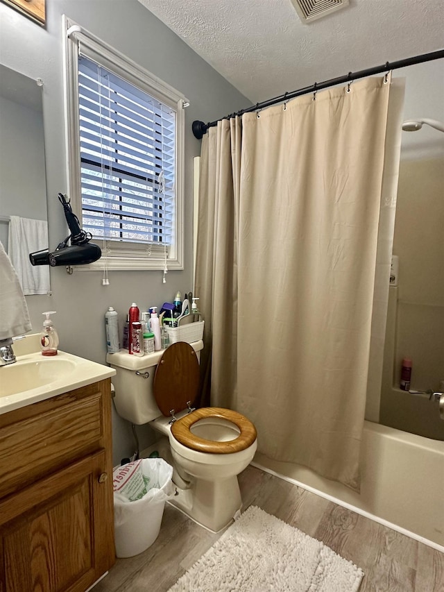 full bathroom with toilet, wood-type flooring, shower / tub combo, a textured ceiling, and vanity