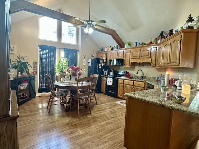 kitchen featuring high vaulted ceiling, light wood-type flooring, ceiling fan, light stone countertops, and black appliances