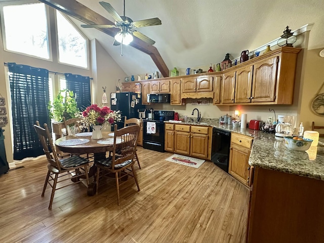 kitchen with sink, black appliances, light hardwood / wood-style floors, stone countertops, and vaulted ceiling