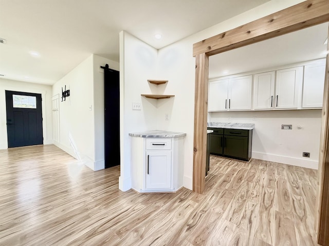 kitchen with white cabinetry, a barn door, and light hardwood / wood-style flooring