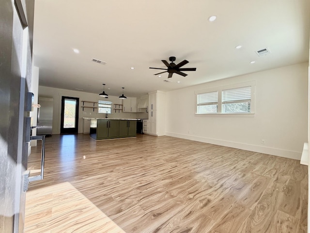 unfurnished living room with plenty of natural light, ceiling fan, and light hardwood / wood-style flooring