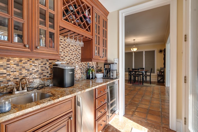 kitchen featuring sink, hanging light fixtures, wine cooler, tasteful backsplash, and light stone countertops