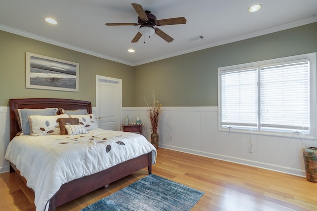 bedroom with crown molding, light hardwood / wood-style floors, and ceiling fan