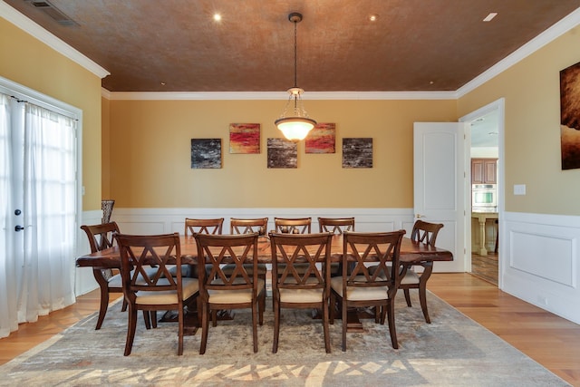 dining space featuring ornamental molding and light wood-type flooring