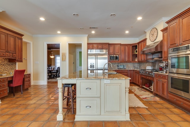 kitchen featuring built in appliances, wall chimney range hood, an island with sink, and a breakfast bar