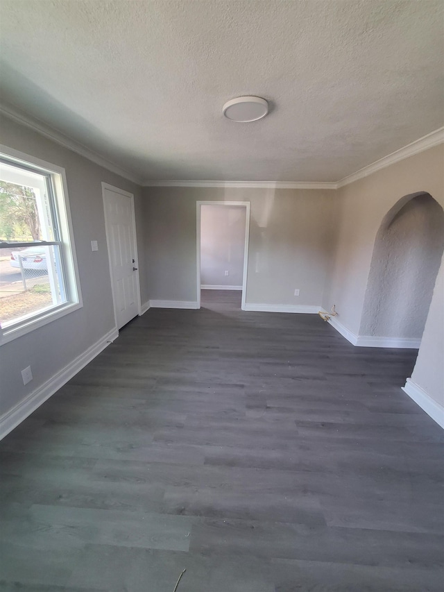 spare room with dark wood-type flooring, ornamental molding, and a textured ceiling