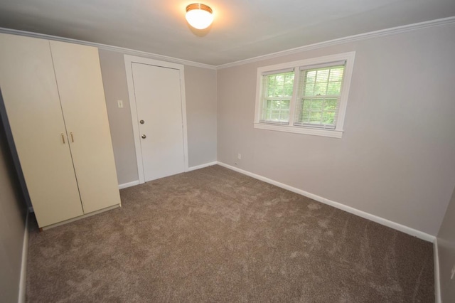 unfurnished bedroom featuring crown molding, dark carpet, and a closet