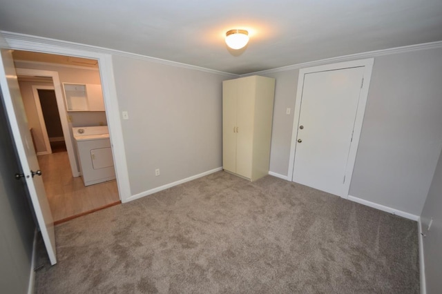 unfurnished bedroom featuring crown molding, washer / dryer, light colored carpet, and a closet