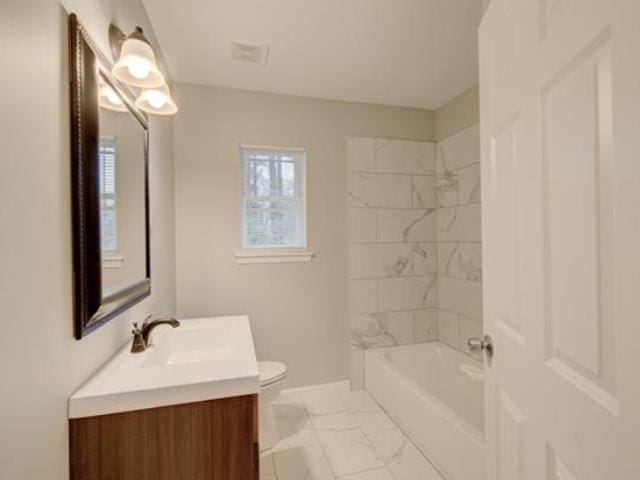 full bathroom with tiled shower / bath combo, vanity, and toilet