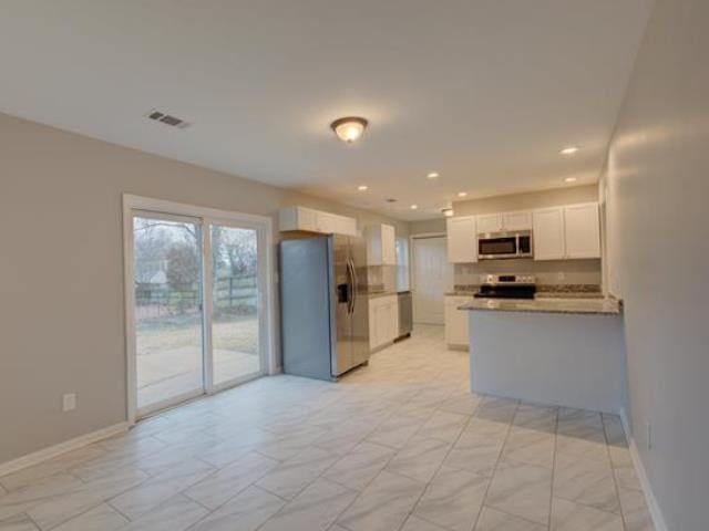 kitchen featuring appliances with stainless steel finishes, kitchen peninsula, and white cabinets