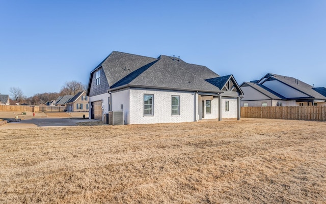 rear view of house with a garage, central air condition unit, and a lawn