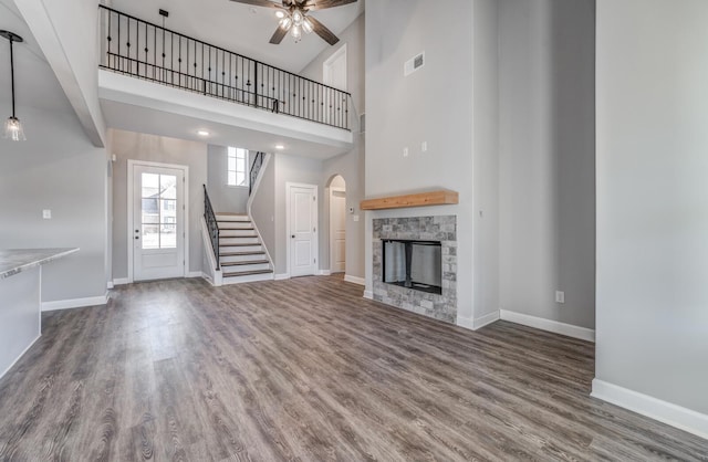 unfurnished living room featuring ceiling fan, a fireplace, hardwood / wood-style floors, and a high ceiling