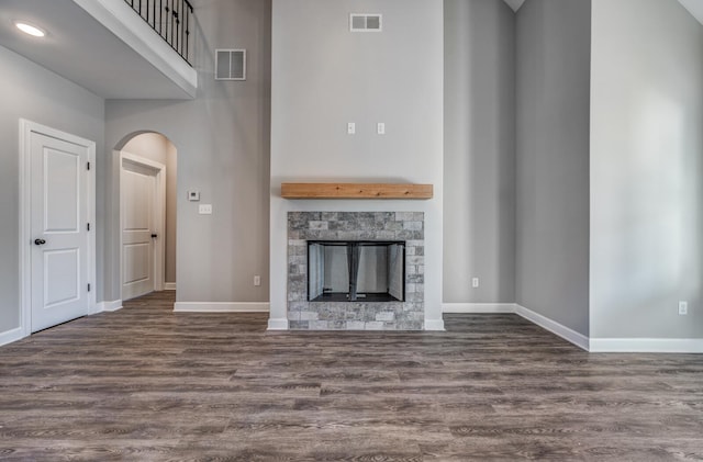 unfurnished living room featuring a stone fireplace and dark hardwood / wood-style floors