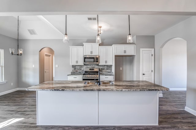 kitchen featuring sink, white cabinetry, hanging light fixtures, appliances with stainless steel finishes, and dark stone counters