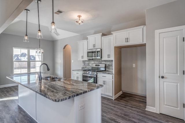 kitchen with pendant lighting, sink, appliances with stainless steel finishes, dark stone countertops, and white cabinets