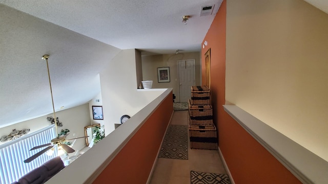 hall with vaulted ceiling and a textured ceiling