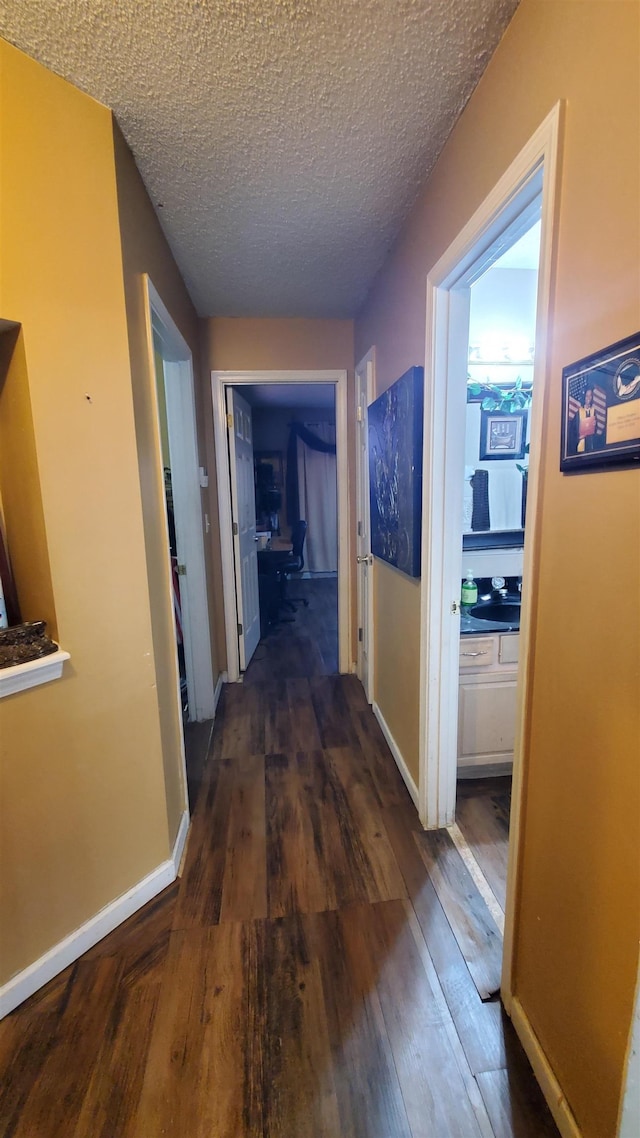 hall with dark wood-type flooring and a textured ceiling