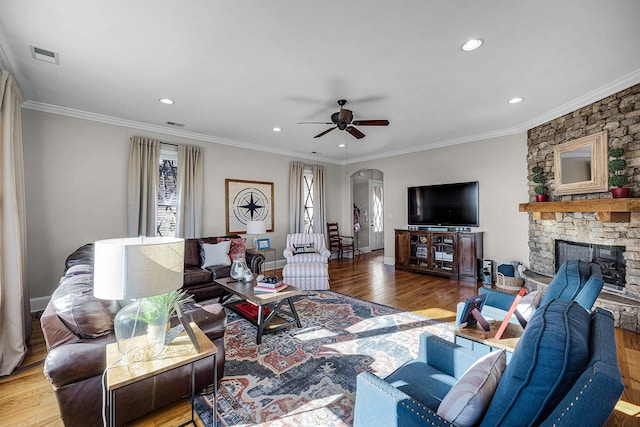 living room featuring hardwood / wood-style flooring, a fireplace, ornamental molding, and ceiling fan