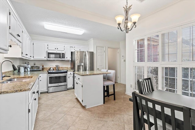 kitchen featuring a kitchen island, appliances with stainless steel finishes, decorative light fixtures, white cabinetry, and sink