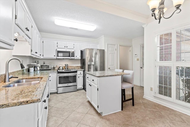 kitchen featuring appliances with stainless steel finishes, sink, white cabinets, a center island, and light stone counters