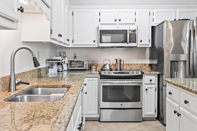 kitchen with stainless steel appliances, white cabinetry, sink, and light stone counters