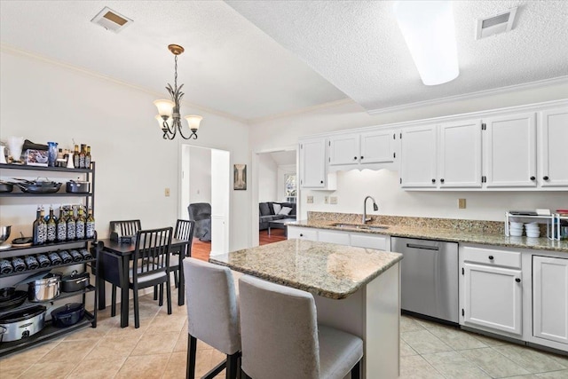 kitchen featuring light stone counters, a textured ceiling, stainless steel dishwasher, a kitchen island, and white cabinets