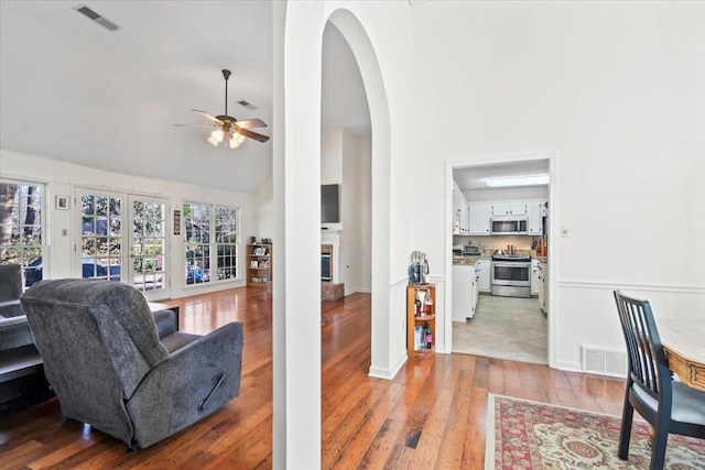 living room with ceiling fan, high vaulted ceiling, and light hardwood / wood-style floors