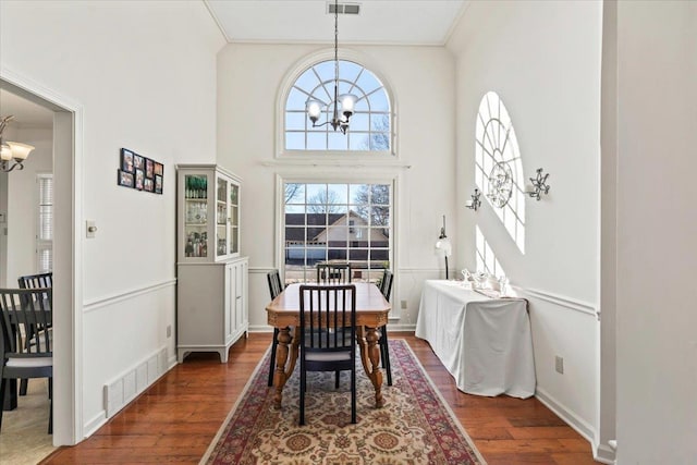 dining area featuring ornamental molding, dark wood-type flooring, and an inviting chandelier