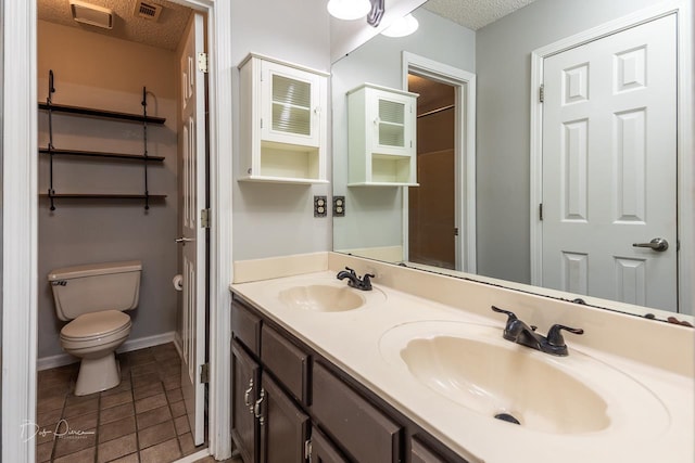 bathroom with tile patterned floors, vanity, toilet, and a textured ceiling