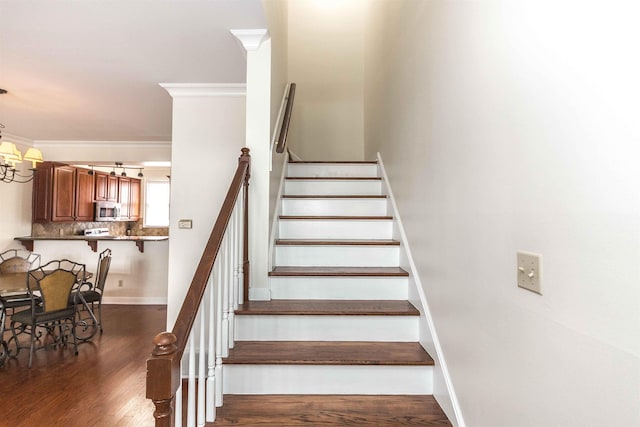 stairway featuring hardwood / wood-style flooring, crown molding, and an inviting chandelier