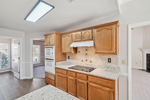 kitchen featuring tasteful backsplash, white appliances, light stone counters, and a tile fireplace