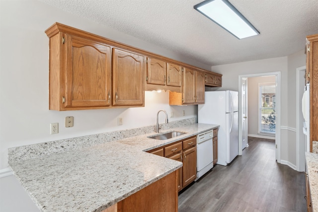 kitchen with sink, light stone counters, a textured ceiling, kitchen peninsula, and white appliances