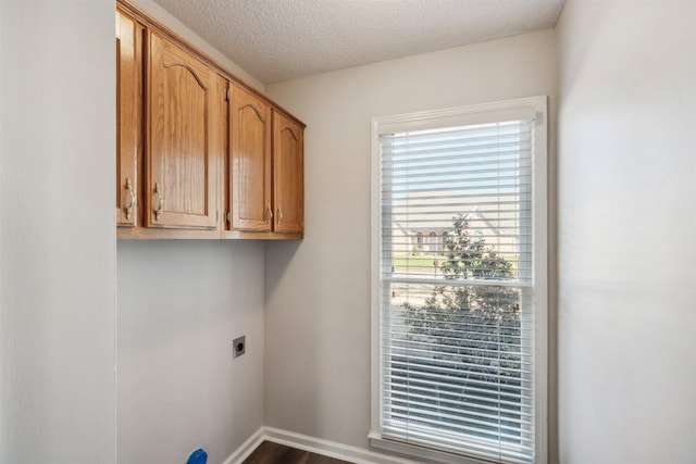 clothes washing area with cabinets, hookup for an electric dryer, hardwood / wood-style floors, and a textured ceiling