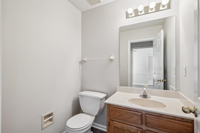 bathroom with vanity, toilet, and a textured ceiling