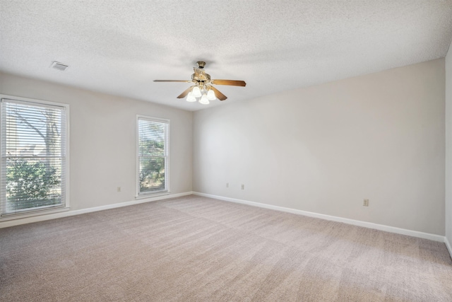 carpeted spare room featuring a textured ceiling, plenty of natural light, and ceiling fan