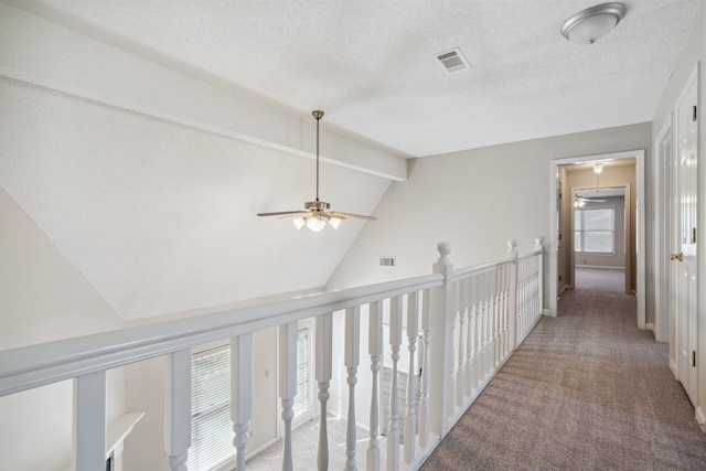 corridor with lofted ceiling with beams, a textured ceiling, and carpet flooring