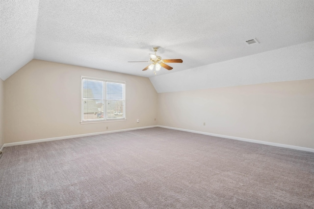 additional living space with ceiling fan, carpet flooring, vaulted ceiling, and a textured ceiling