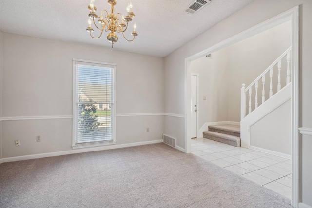 spare room featuring light tile patterned flooring, a textured ceiling, and an inviting chandelier