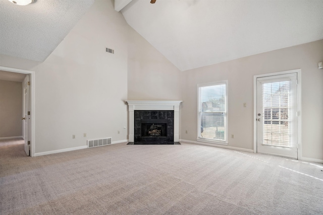 unfurnished living room featuring beam ceiling, high vaulted ceiling, light carpet, a textured ceiling, and a fireplace