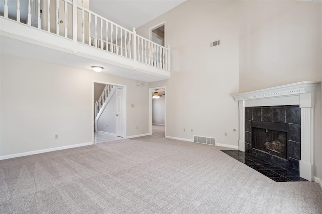 unfurnished living room with a high ceiling, carpet flooring, and a fireplace