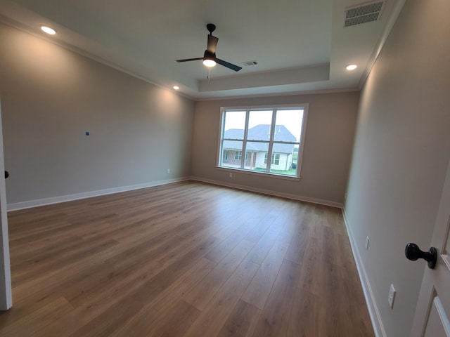 unfurnished room with wood-type flooring, ornamental molding, ceiling fan, a tray ceiling, and a mountain view