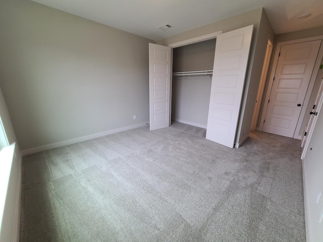 unfurnished bedroom featuring light carpet and a closet