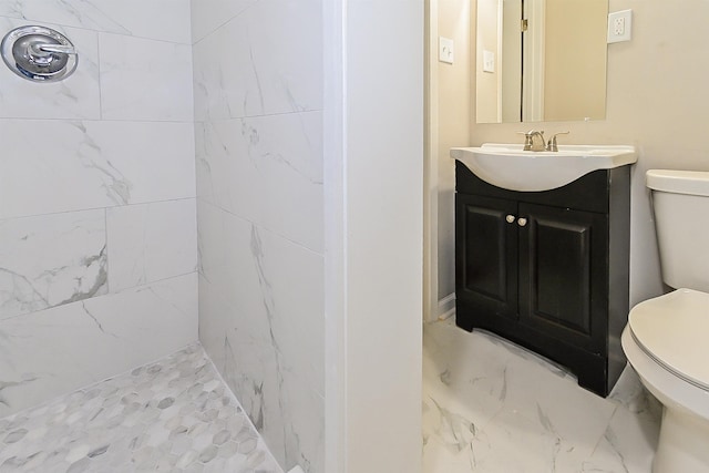 bathroom with vanity, tiled shower, and toilet